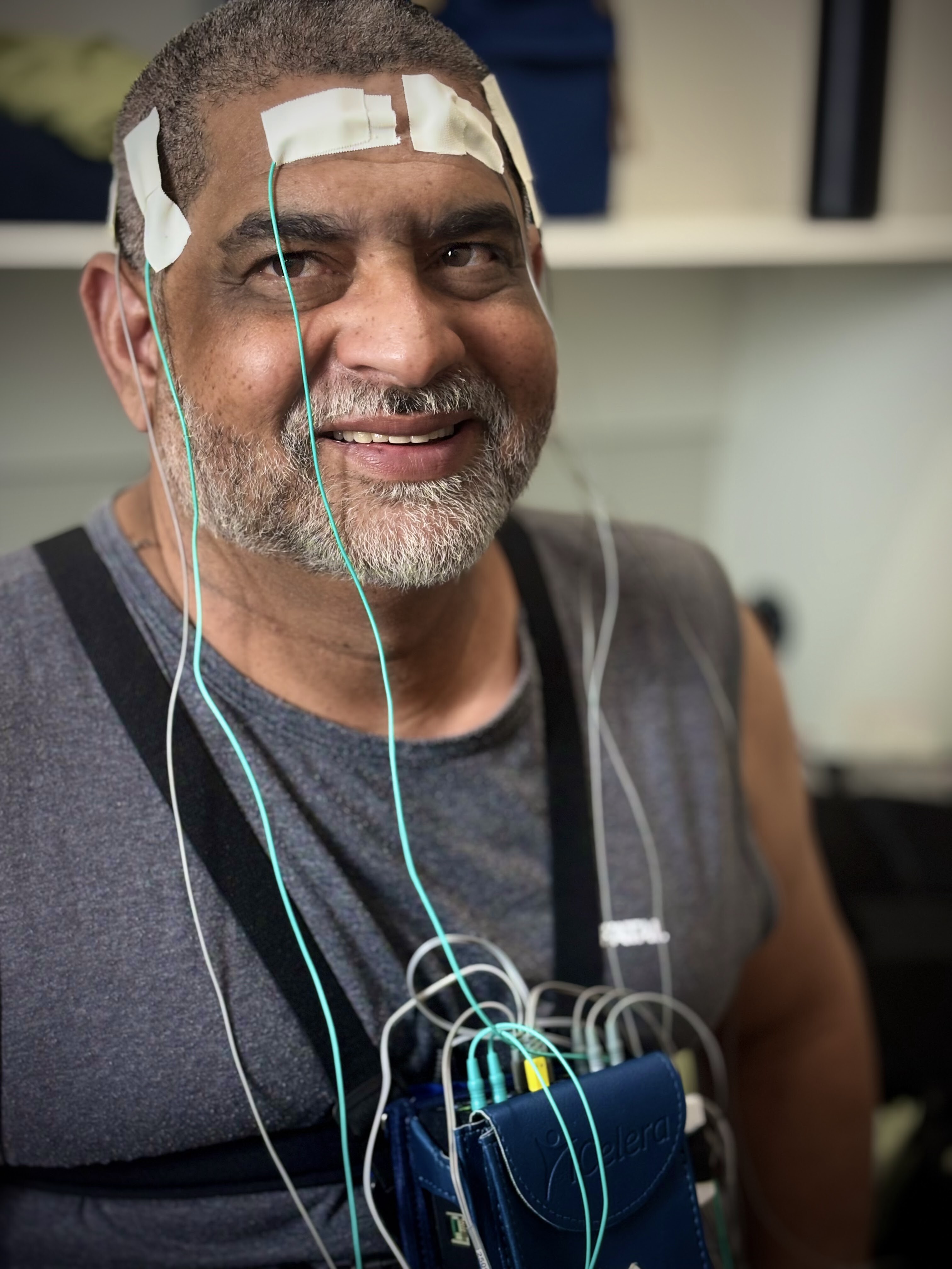 Paciente sorrindo com sensores de polissonografia instalados